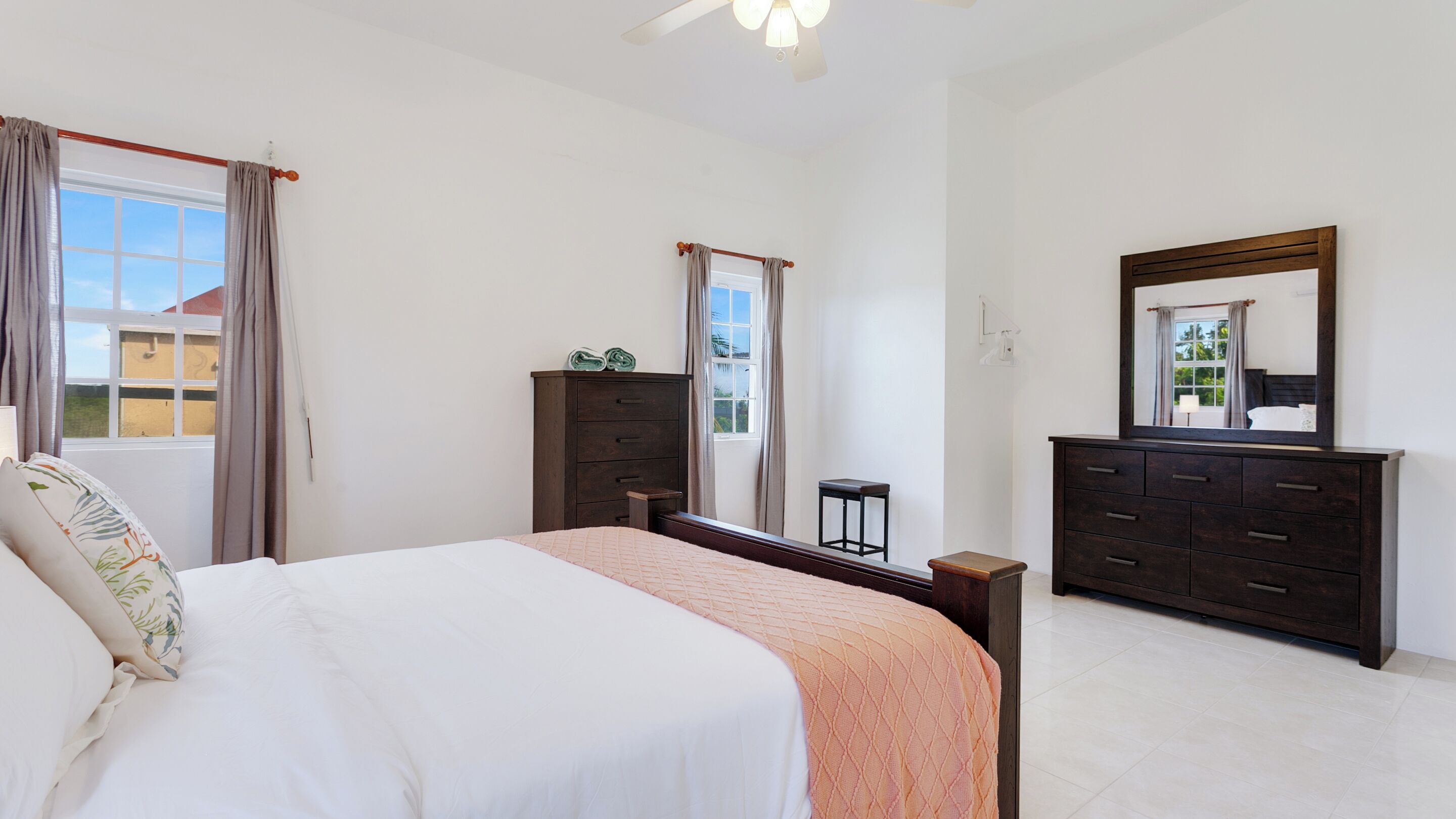 Un dormitorio con una cama, un aparador, un espejo y una ventana con cortinas.