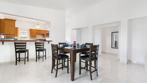 A modern kitchen with wooden cabinets, a dining area with a wooden table and chairs, and a white tiled floor. - Spacious 3-bedroom, 2-bathroom apartment with AC in The Valley (The Valley)