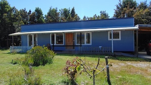 Een blauw huis met twee verdiepingen, een voortuin, een omheinde tuin en een garage.