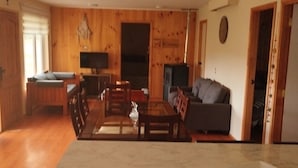Een woonkamer met houten lambrisering, een bank, salontafel en televisie.