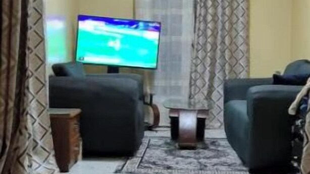 Een hotelkamer met een bed, een televisie, twee banken en een kamerkleed met een patroon.