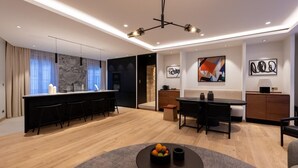 A modern kitchen with a marble backsplash, a dining area with a round table, and a living space with a sofa and a coffee table. - Les Suites by Cave Vauban - Suite Caria (Dijon)
