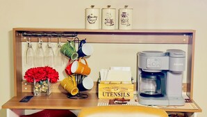 Eine Küchenarbeitsplatte mit Kaffeemaschine, Geschirr und bunten Tassen.