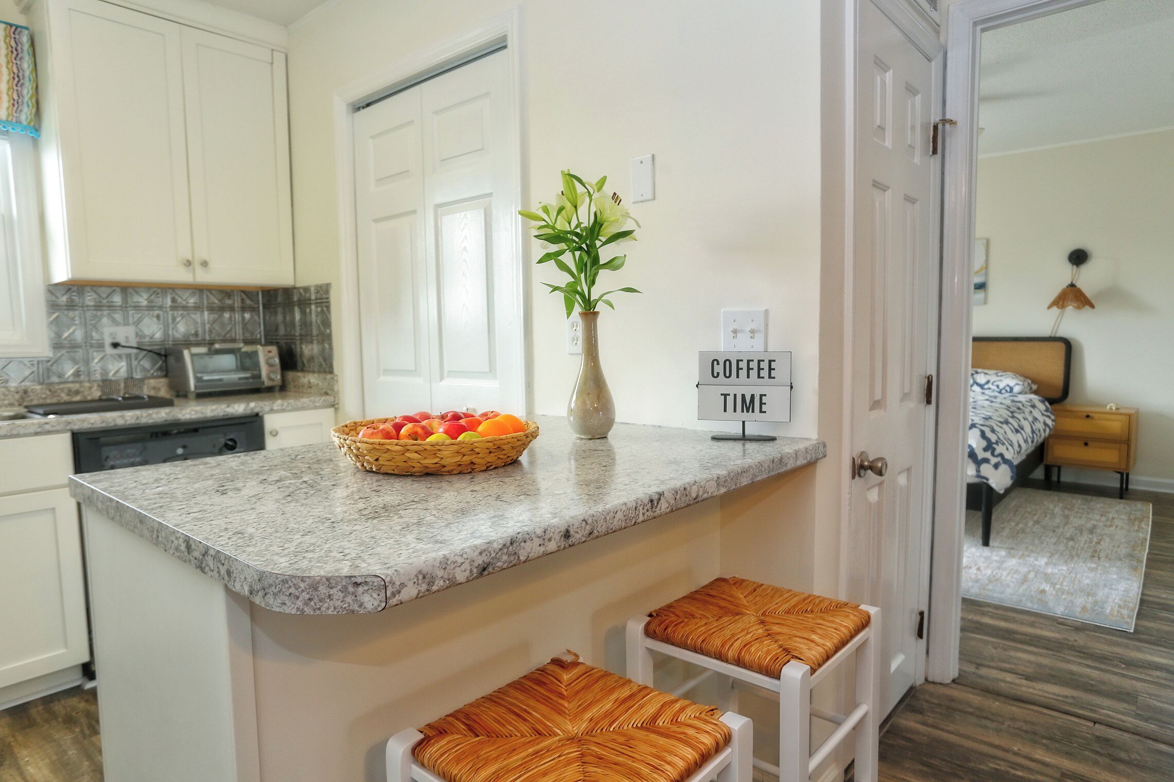 A kitchen with a granite countertop, a toaster, a vase with flowers, and a sign that says "COFFEE TIME".