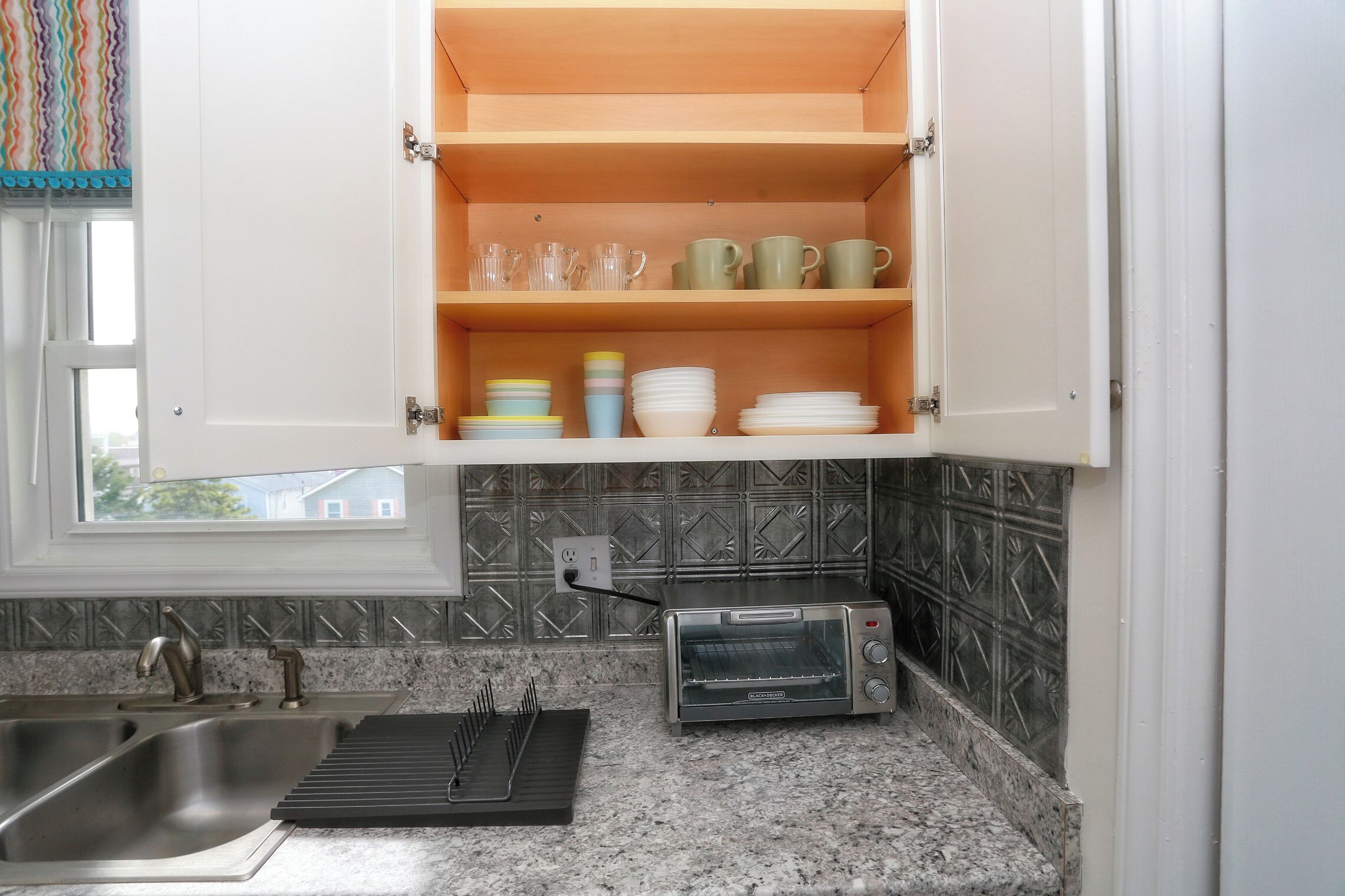 Cozinha equipada com forno embutido, pia e janela com vista para uma casa.