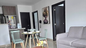 Ein modernes Wohnzimmer mit grauem Sofa, einem Holztisch und einem Essbereich mit rundem Tisch und Stühlen.