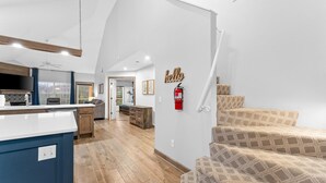 A spacious living area with a kitchen, a staircase, and a fire extinguisher on the wall. - Gorgeous Golf Views Condo in the heart of Branson (sleeps 8) (Branson)
