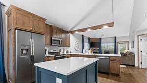 A modern kitchen with wooden cabinets, stainless steel appliances, and a blue island. - Gorgeous Golf Views Condo in the heart of Branson (sleeps 8) (Branson)