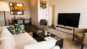 Un salon comprenant un canapé, une table basse, un téléviseur et un coin repas avec des chaises et une table.