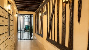 Un couloir avec des poutres en bois apparentes, une porte en métal et une rangée d’armoires de rangement.