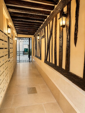 A hallway with exposed wooden beams, a metal gate, and a row of storage cabinets.