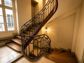 A spiral staircase with a wooden finish and black metal railings.