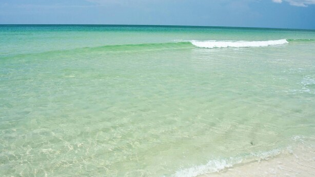 A beach with clear turquoise water and gentle waves.