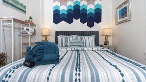 A neatly made bed with striped bedding, a bedside lamp, and a wall art piece.