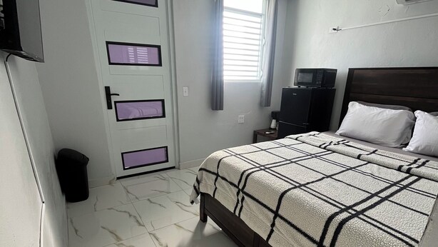 A bedroom with a bed, a television, a small table, and a window with curtains. - Molinos House 3 (Santa Isabel)