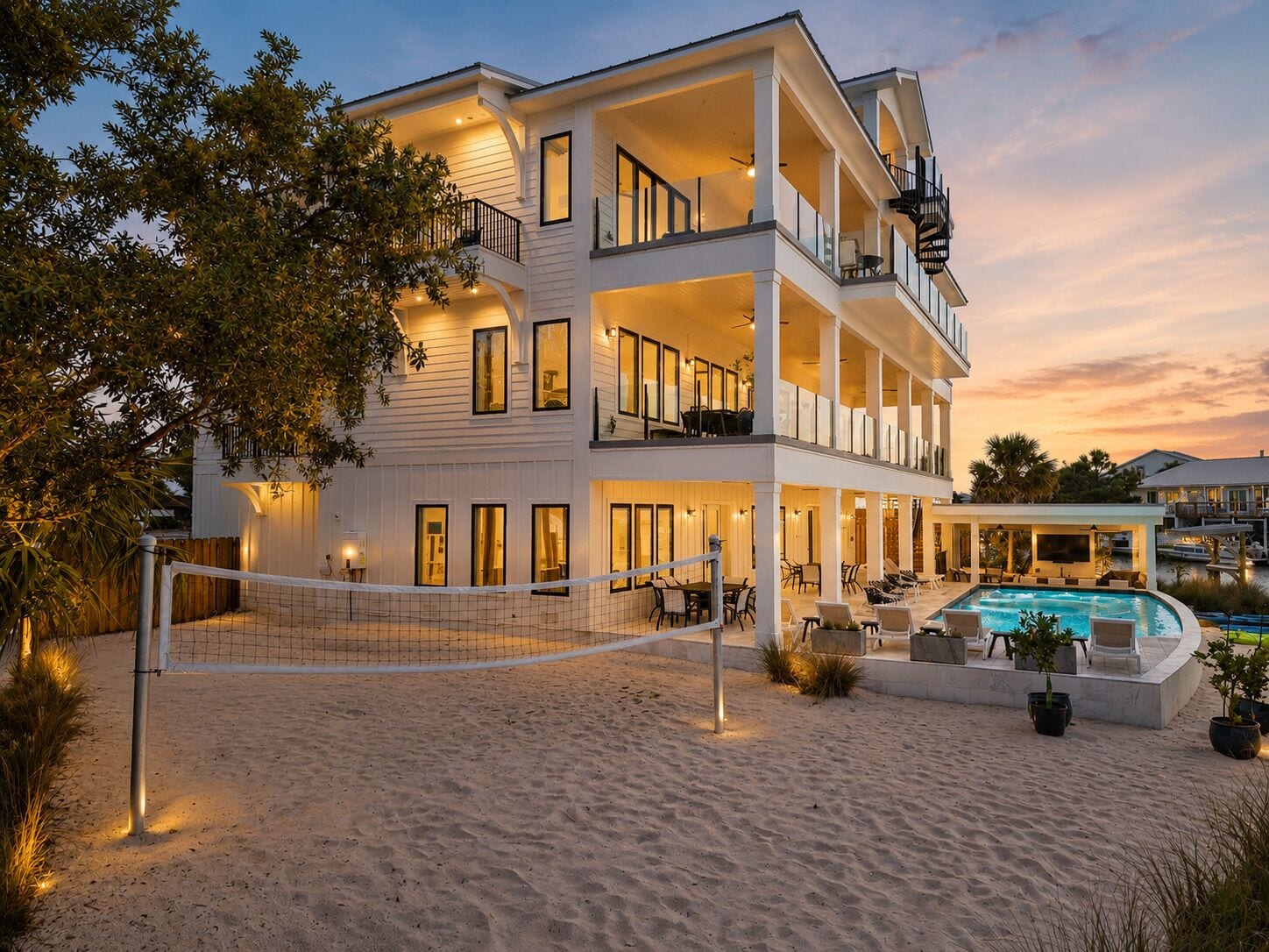 A two-story beachfront property with a swimming pool and outdoor seating area.