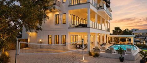 A two-story beachfront property with a swimming pool and outdoor seating area.