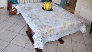 Un coin repas avec une table dressée pour deux personnes, un lustre et une vue sur la cuisine.