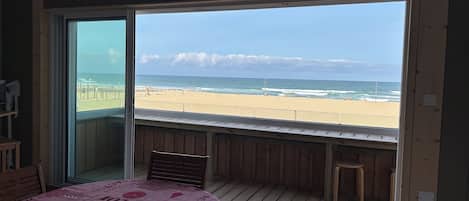 A room with a large sliding glass door leading to a beach view.