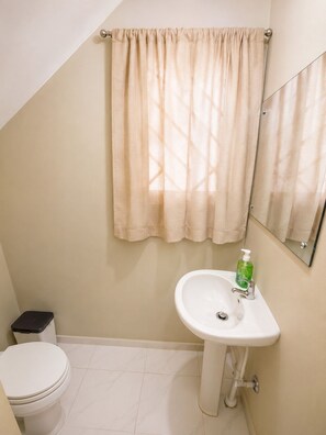 Une salle de bain avec des toilettes, un lavabo et un miroir.