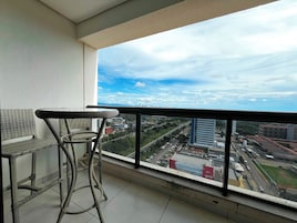 Un balcón con mobiliario de mimbre y vista a la ciudad.