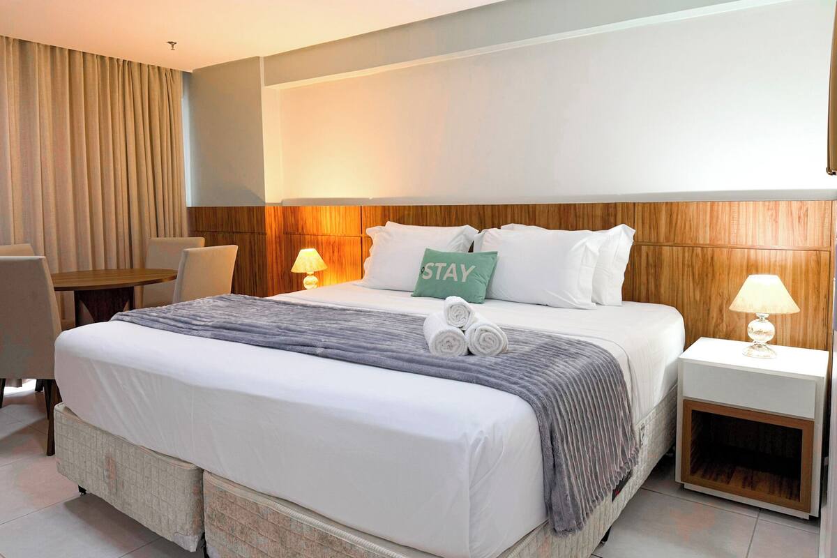 A hotel room with a large bed, two bedside tables with lamps, a chair, and a desk.