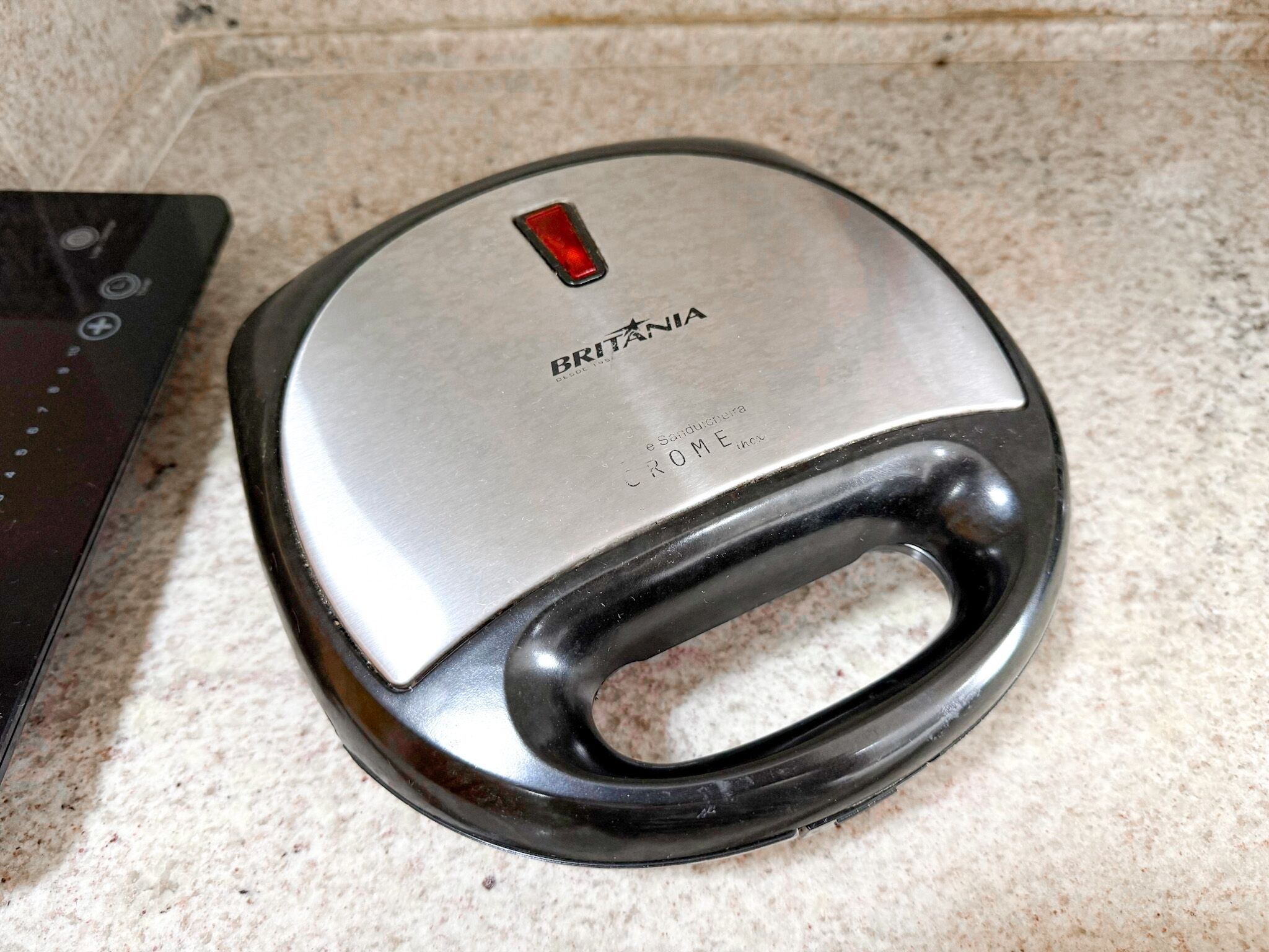 Un appareil de cuisine doté d’un dessus métallique et d’un manche noir.