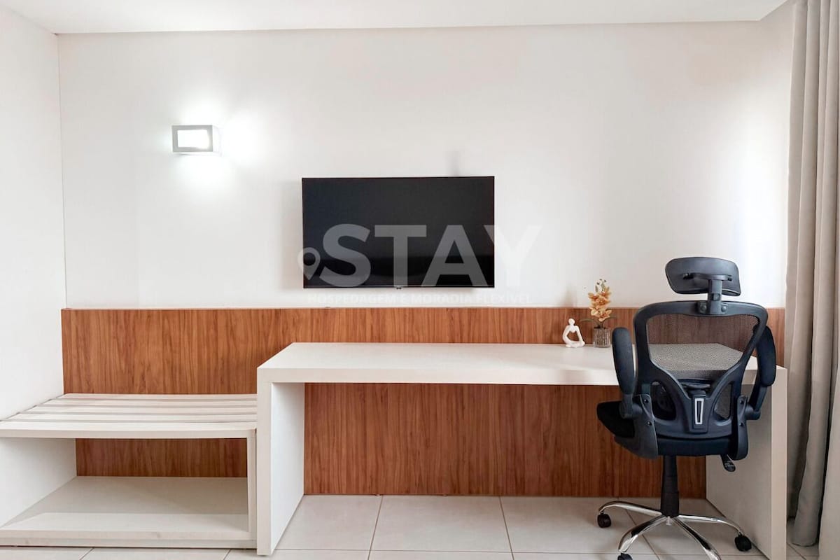 A modern reception desk with a flat-screen TV, a wooden accent wall, and a black office chair.
