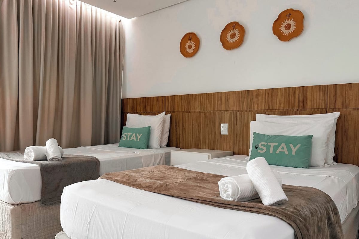A hotel room with two beds, a wooden headboard, and decorative wall plates.