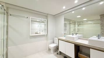 A modern bathroom with two sinks, a toilet, and a glass shower enclosure.