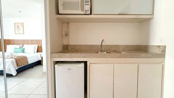 Una kitchenette compacta con microondas, pileta y heladera pequeña.