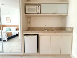 Una kitchenette compacta con microondas, pileta y heladera pequeña.