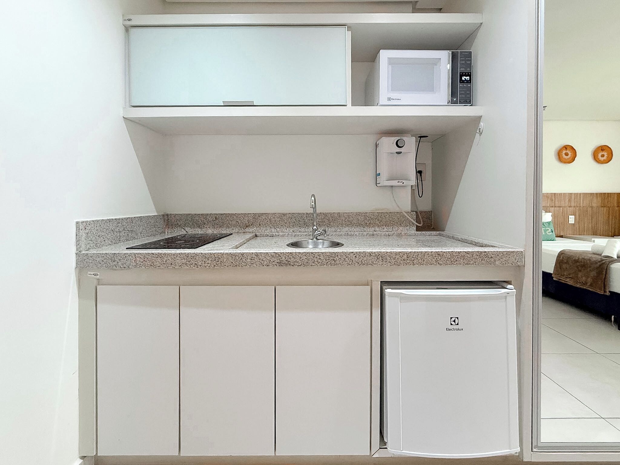 A compact kitchenette with a microwave, a small sink, and a compact refrigerator.