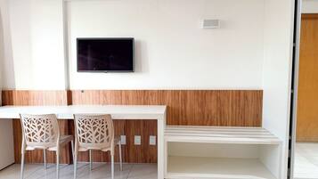 Una habitación moderna con un escritorio blanco, dos sillas, un televisor de pantalla plana montado en la pared y una pared de acento de madera.