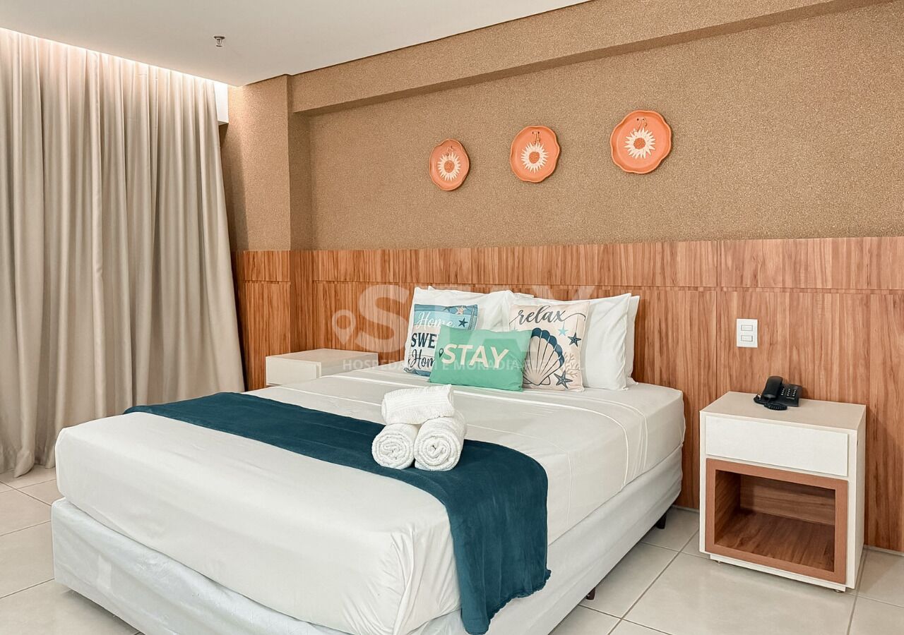 A hotel room with a bed, a nightstand, and a wall with decorative plates.