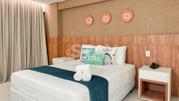 Habitación de hotel con cama, mesita de noche y una pared decorada con placas.
