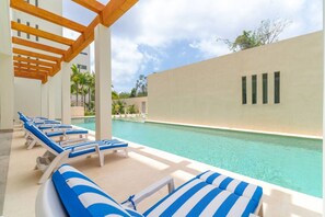Un espace aménagé au bord de la piscine, avec des chaises longues et une vue dégagée sur la piscine.