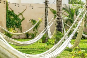 Un hamac dans un jardin luxuriant, agrémenté de palmiers et de verdure.