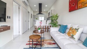 Uma sala de estar moderna com um sofá branco, uma mesa de centro e uma televisão. Uma escada leva a outro andar.