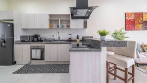 Cozinha moderna com ilha integrada, eletrodomésticos de aço inoxidável e um espaço de refeições com um banquinho.