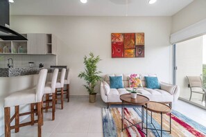 Un soggiorno moderno con un divano, poltrone, un tavolino da caffè e un quadro appeso al muro.