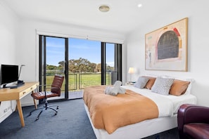 A hotel room with a bed, a desk, a chair, a TV, and a large window with a view of trees. - Magic Driftwood (Torquay)