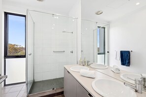A modern bathroom with a glass shower enclosure, two sinks, and a large mirror. - Magic Driftwood (Torquay)