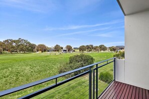 A balcony with a view of a grassy field and buildings in the distance. - Magic Driftwood (Torquay)