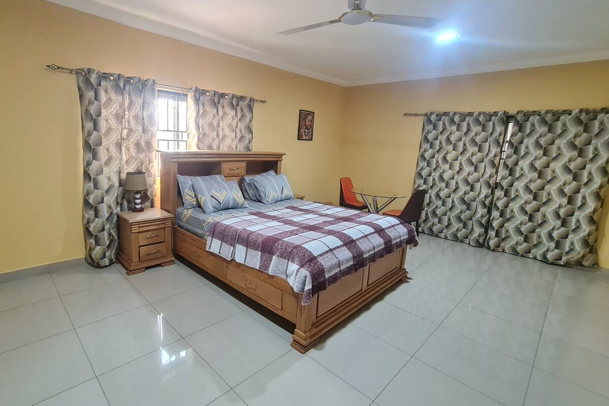 A bedroom with a bed, nightstands, a ceiling fan, and curtains.