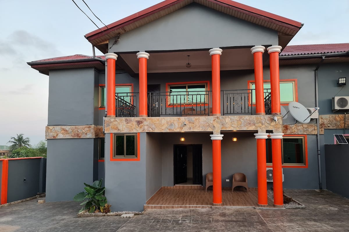 A two-story building with a balcony, columns, and a satellite dish.