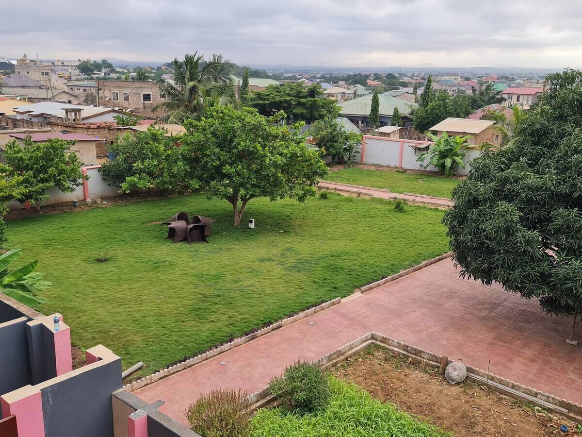 A residential area with a well-maintained lawn, a patio area with outdoor furniture, and a view of surrounding buildings.