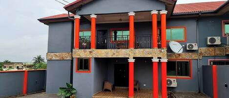 Un bâtiment à deux étages, avec un toit rouge, des murs gris et des piliers rouges.