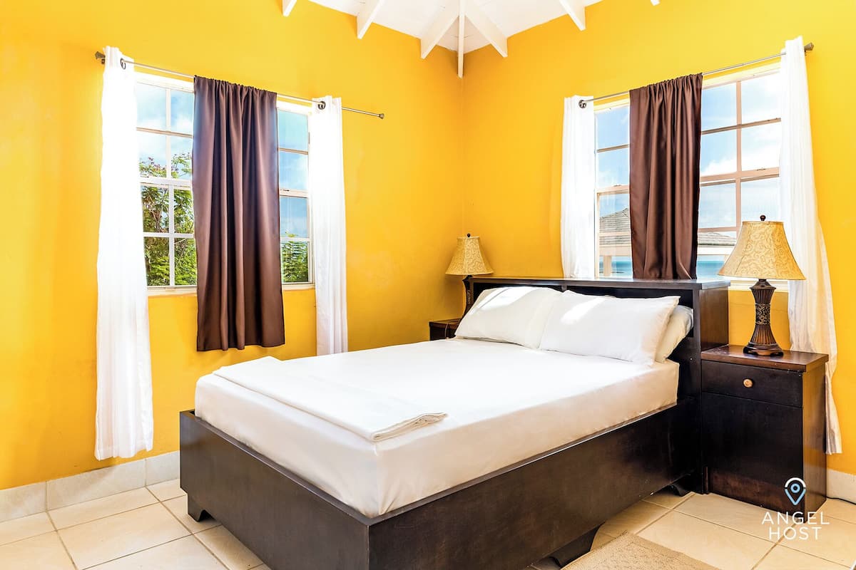 A bedroom with a bed, two nightstands, a lamp, and curtains.