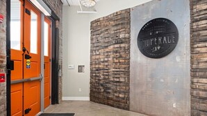 A hallway with an orange door, a brick wall, and a plaque reading "Peoria, Illinois, 2014". - Cooperage 214 | Mid-century 1BD Loft | Peoria (Peoria)